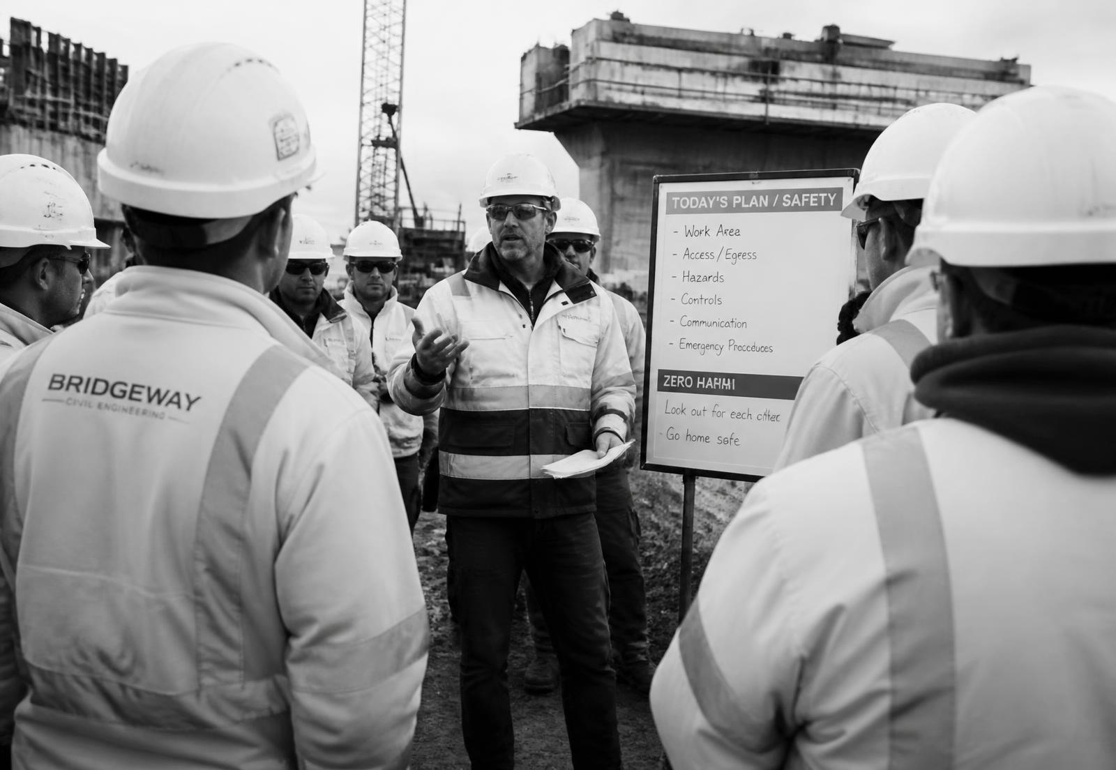 Site crew in personal protective equipment during a toolbox meeting